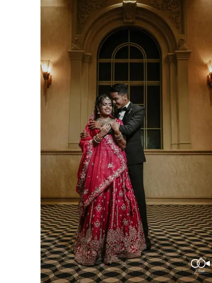 A full-length portrait of the couple, the groom embracing the bride from behind, showcasing her beautiful lehenga.