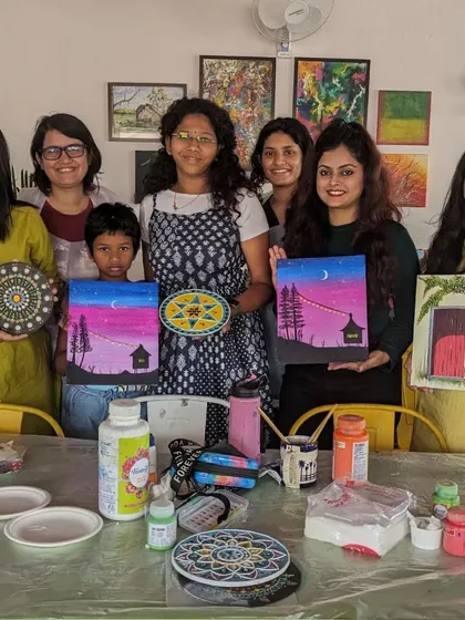 A group photo from a workshop, showcasing the beautiful canvas paintings and dot mandalas created.