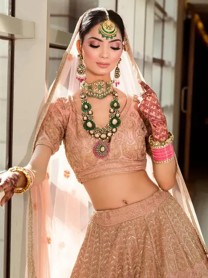 A serene portrait that showcases the delicate color palette and intricate work of a pastel bridal lehenga, set against a natural backdrop.