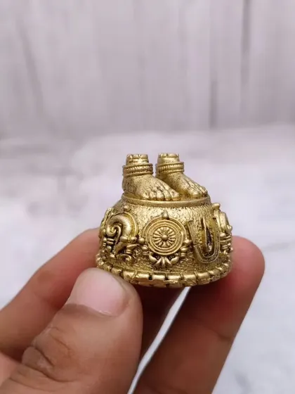 A close-up of the brass Balaji Padam idol, showing the detailed symbols of Shanku, Chakra, and Naamam.