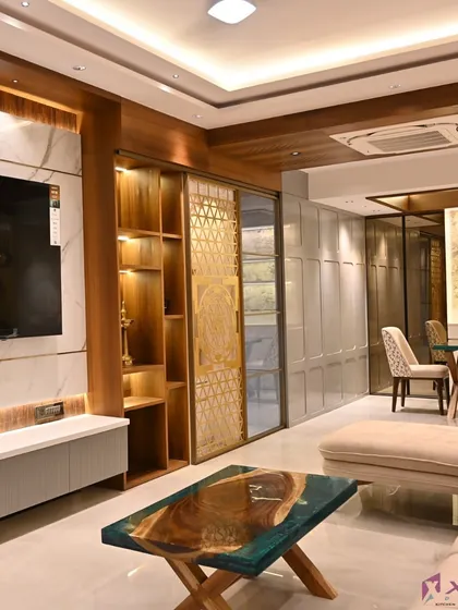This wide view shows how we integrate different elements like the TV unit, a pooja space with a jaali door, and the living room seating into one harmonious design using wood and marble textures.