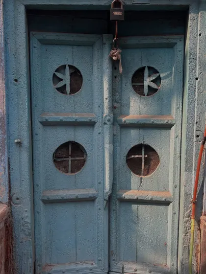 A rustic blue door with unique circular cutouts. The craftsmanship and design of these old doors are a fascinating part of our architectural discussions on the walk.