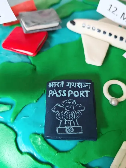 A close-up of the travel-themed cake, showing the tiny, hand-sculpted Indian passport and other travel mementos.