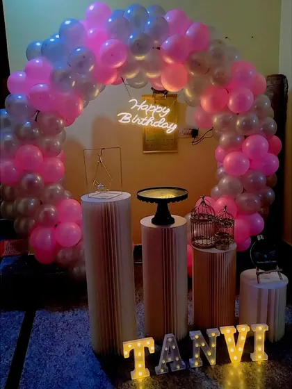 A simple home birthday setup with a pink and silver balloon ring and marquee letters.