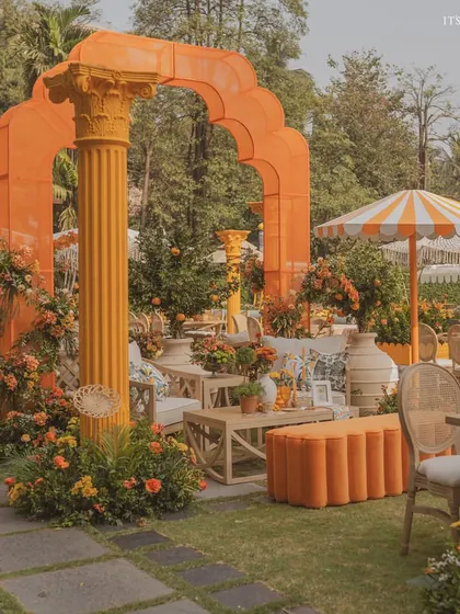 A wide view of the 'Orange Orchard' Haldi, where we used bold orange architectural elements, cane furniture, and lush greenery to create a vibrant atmosphere.