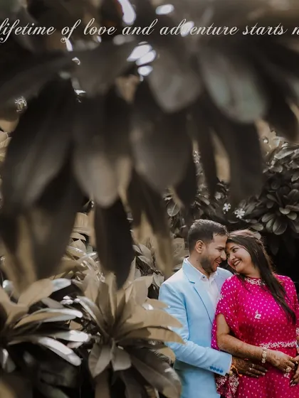 Elegant portraits of a couple in a lush garden setting, likely at a palace hotel like Samode. The vibrant pink and blue outfits create a beautiful contrast with the greenery.