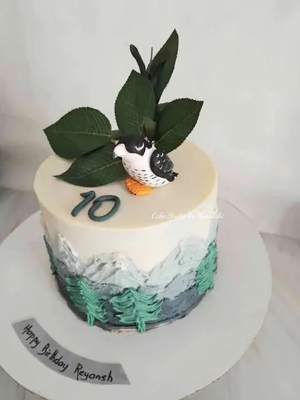 A beautiful falcon themed cake with hand-piped buttercream mountains. This is a unique and artistic design for a nature-loving 10-year-old.