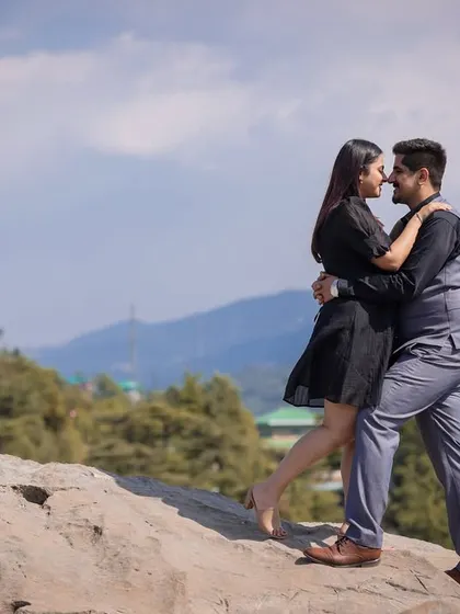 A dynamic and romantic pose on a large rock, with the beautiful Shimla hills in the background. This shot captures movement and affection.