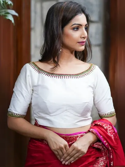 A classic white boat-neck blouse with delicate embroidery along the neckline and cuffs.