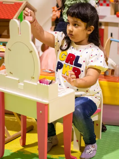 A little girl getting ready at the play vanity, showing off her "GRL PWR" shirt. We love empowering kids through play.