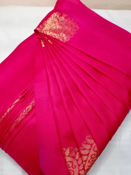 This bright pink silk saree is pleated and ready to be draped. The pleats are set to highlight the gold butti work on the fabric.