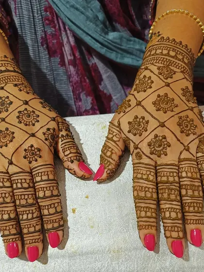 This design focuses on a classic jaali, or net pattern, covering the back of the hands. The small floral motifs inside the grid add a touch of delicate detail.