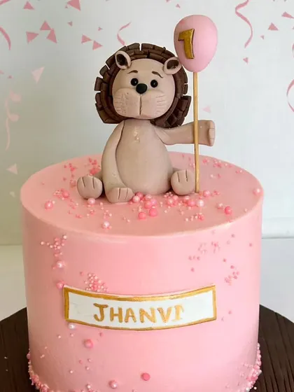A sweet and simple first birthday cake featuring an adorable fondant lion holding a balloon. This design is perfect for a jungle or animal-themed party for a one-year-old.