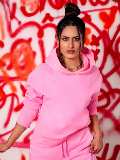 A close-up from the graffiti series, focusing on the attitude and expression. The top knot hairstyle and chain necklace complete the look, making it a strong editorial-style portrait.