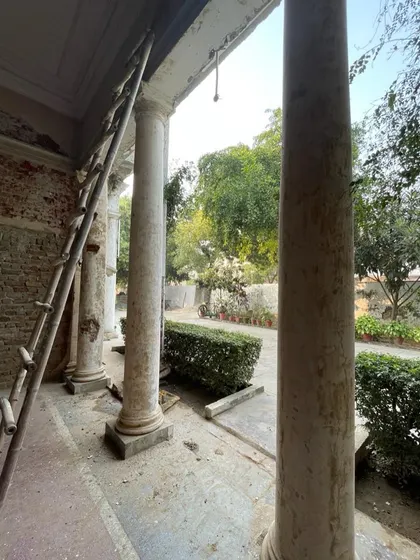 The process begins. The grand colonial-style columns of the portico are prepared for restoration, with the original brickwork exposed.