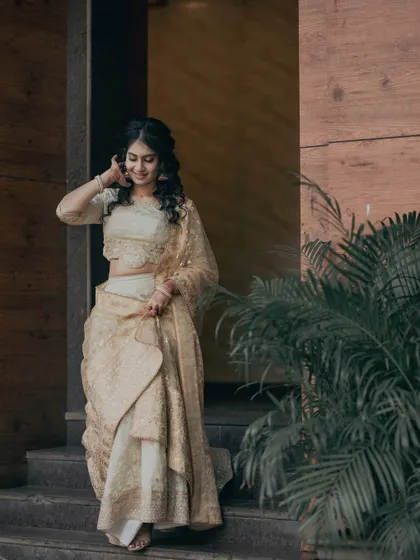 A full-length shot of Kavya's stunning ivory and gold engagement outfit. The soft, glowing makeup complements the elegance of her attire.