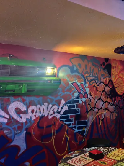 A different section of the cafe mural, showing how the graffiti style integrates with other elements like the front of a car mounted on the wall. It's all about creating a total vibe shift.
