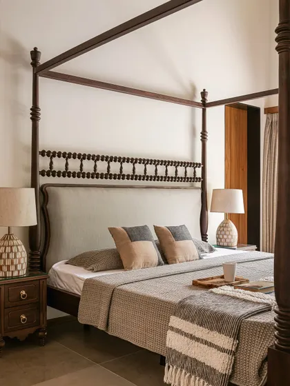 A close-up of the four-poster bed, showing the detailed turned-wood posts and the simple, comfortable bedding.