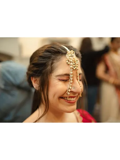 The bride, Amanda, beaming with a beautiful, natural smile as she gets her hair and makeup done for her Indian wedding.