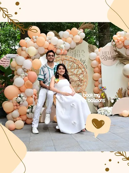 This beautiful outdoor baby shower featured a stunning balloon arrangement in shades of peach and cream. The happy couple posed in front of the boho chic decor, which included pampas grass and a custom "Hello Baby" sign.