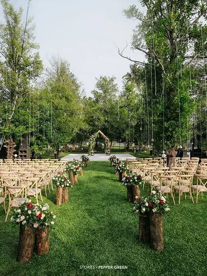 The stunning outdoor setup for Ameera and Richard's wedding, with wooden chairs and floral arrangements on log stumps. The rustic elegance is beautifully captured.