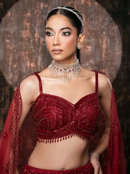 A mid-shot focusing on the intricately beaded blouse and modern silhouette of a red bridal lehenga.