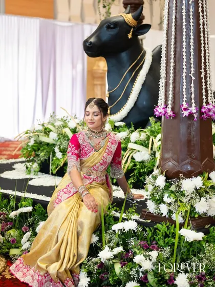 A regal portrait of the bride's sister, seated amidst beautiful floral decor. Her makeup is flawless, enhancing her elegant and traditional attire.
