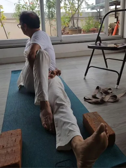 A senior practitioner demonstrates a seated twist using props, highlighting that our TTC teaches modifications for all ages and abilities.