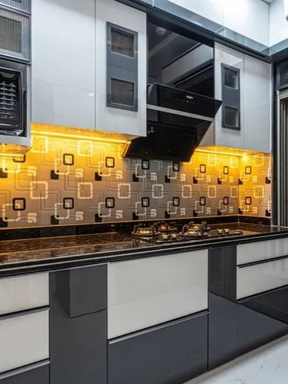 A kitchen designed with a bold, graphic backsplash and two-tone cabinets in grey and white. The layout includes space for a built-in microwave and oven, showcasing our expertise in appliance integration.
