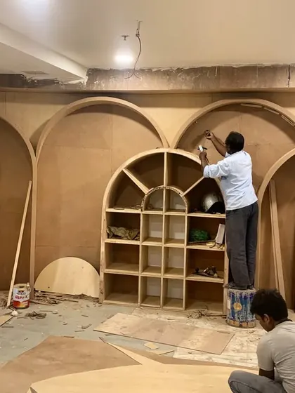 A team of carpenters works on an intricate plywood wall featuring a series of arches. This image captures the skill and precision involved in executing our custom designs.