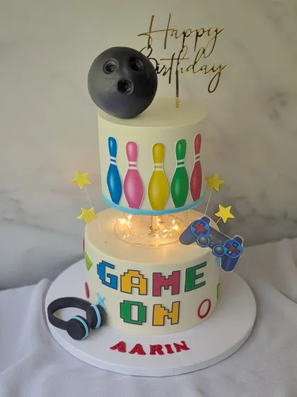 It's a strike for gamer boy Aarin! This two-tier cake combines his love for bowling and gaming, with a bowling ball on top and a "Game On" pixelated design below.