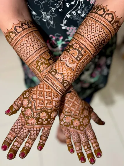 A crossed-arm pose of Chaitra's mehendi, showing the full extent of the detailed artwork.