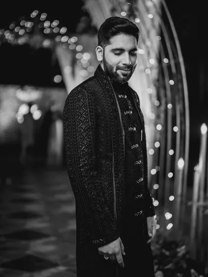 A handsome black and white portrait of the groom, Kartik, against a beautifully lit background.
