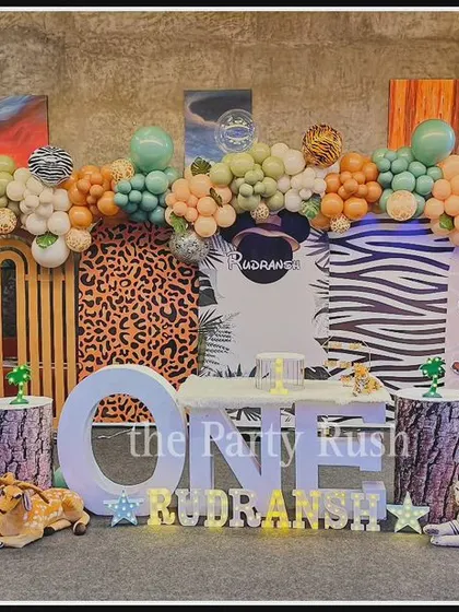 Rudransh's first birthday combined a jungle theme with Mickey Mouse safari elements. The decor features animal print backdrops and a mix of classic jungle animals with a Mickey Mouse cutout.