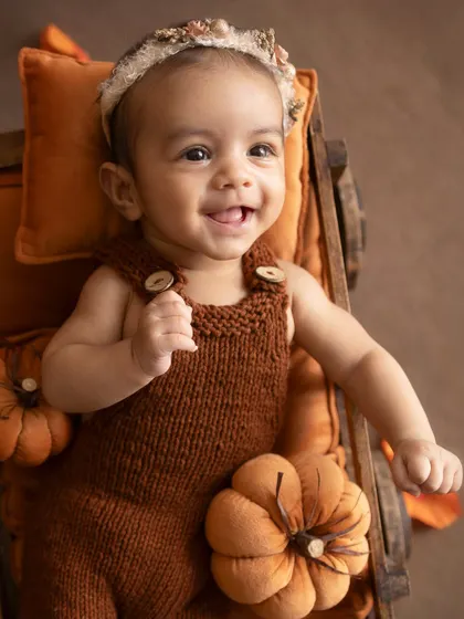 A happy, playful expression. This baby is full of smiles and ready for her close-up in this adorable autumn setup.