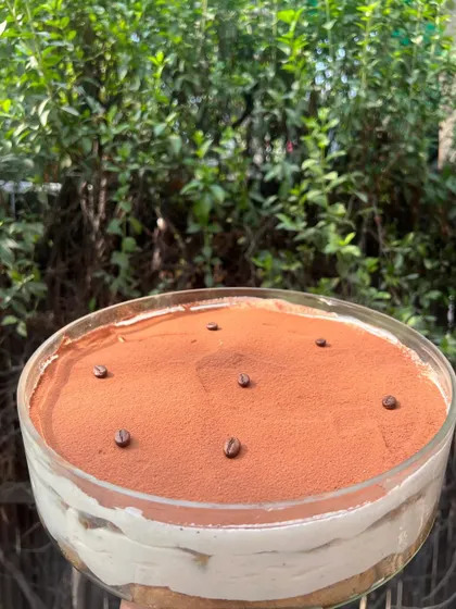 My classic Tiramisu in a large glass bowl, dusted with cocoa and topped with coffee beans. It’s a timeless Italian dessert that I make with authentic ingredients.