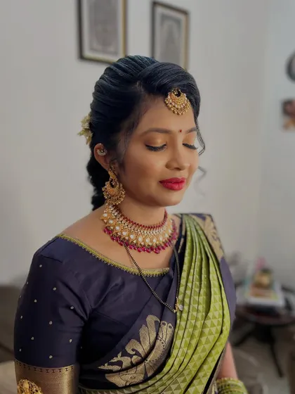 A serene shot showing the details of her bridal makeup. The soft eyeshadow, defined brows, and bold red lip create a balanced and elegant look that enhances her natural beauty.