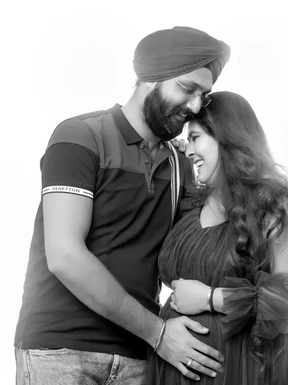 A tender black and white photo of a couple during their maternity shoot. The husband gently rests his head on his wife's, showing their close bond and happiness.