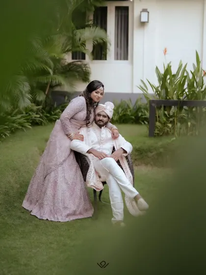 A romantic outdoor portrait of a couple, with the bride seated on the groom's lap.