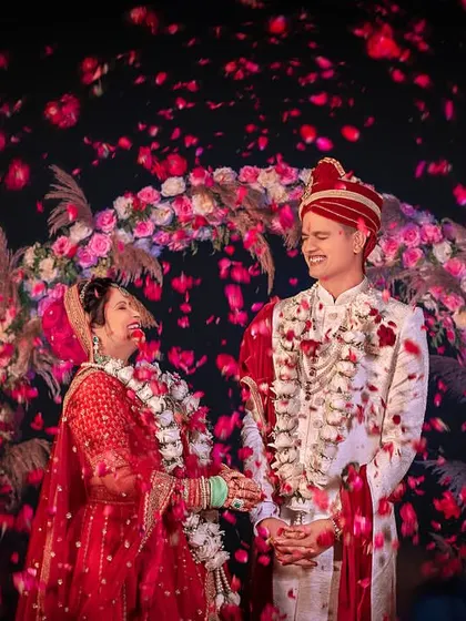 Showered with flower petals, the couple shares a laugh during their varmala ceremony. A moment of pure, unadulterated joy.