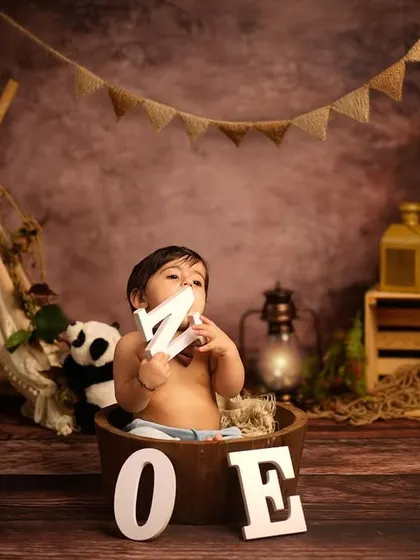 Exploring the setup before the cake arrives. This little one is enjoying the props in our jungle-themed first birthday session, holding the letters that spell out "ONE".