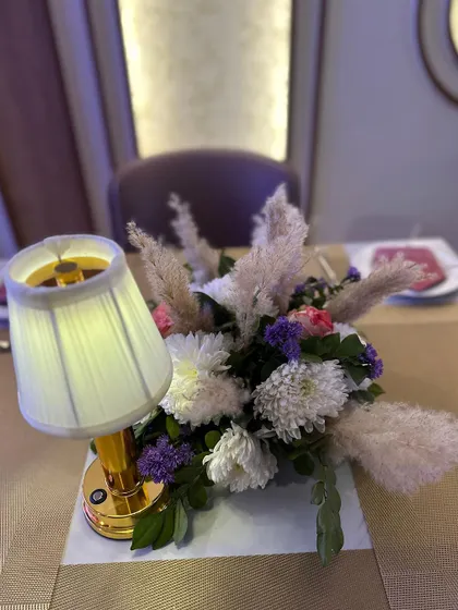 A charming table centerpiece combining a floral arrangement with a miniature lamp.
