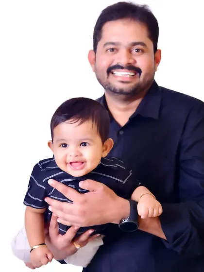 A proud father holds his smiling baby boy. This clean, classic studio portrait against a white background puts all the focus on their happy expressions and the bond they share.