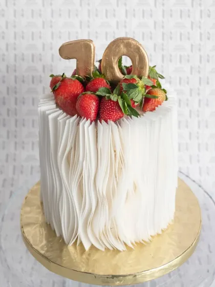 An elegant cake with a unique textured finish, topped with fresh strawberries for a 10th anniversary.