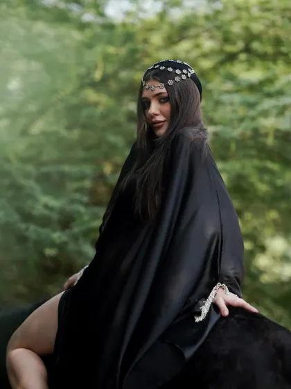 The color version of a shot from the Arabic-themed series, showing the model in a black robe against the lush green background.