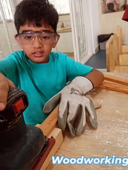 Wearing safety gloves and goggles, this student is focused on sanding his project pieces. We teach that a smooth finish is a sign of great craftsmanship.