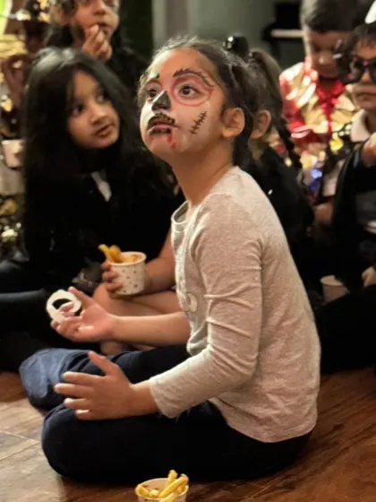 Another angle of this amazing skeleton face paint, showing the child completely engrossed in the party's entertainment.