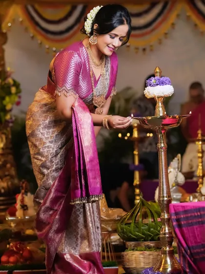 A serene moment as Hemalatha lights a traditional lamp. The shimmering saree looks beautiful in the warm light.