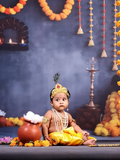 A six-month-old baby boy dressed as Lord Krishna. The sitter milestone is a great time for this theme, as babies can sit up and interact with the props, like the pot of butter.
