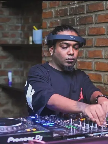 In the zone, spinning a hip-hop set. The brick wall background gives this spot a raw, urban feel.